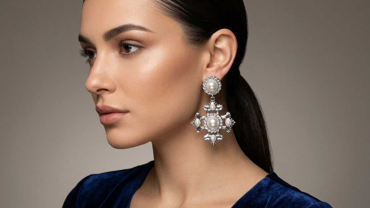 Model wearing an ornate silver-tone drop earring with pearl-effect details and clear stones
