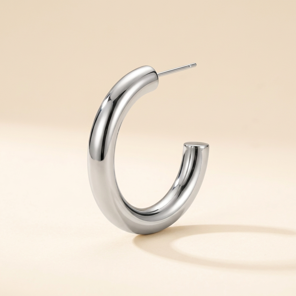 Silver-tone chunky stainless steel hoop earring with visible post on ivory background