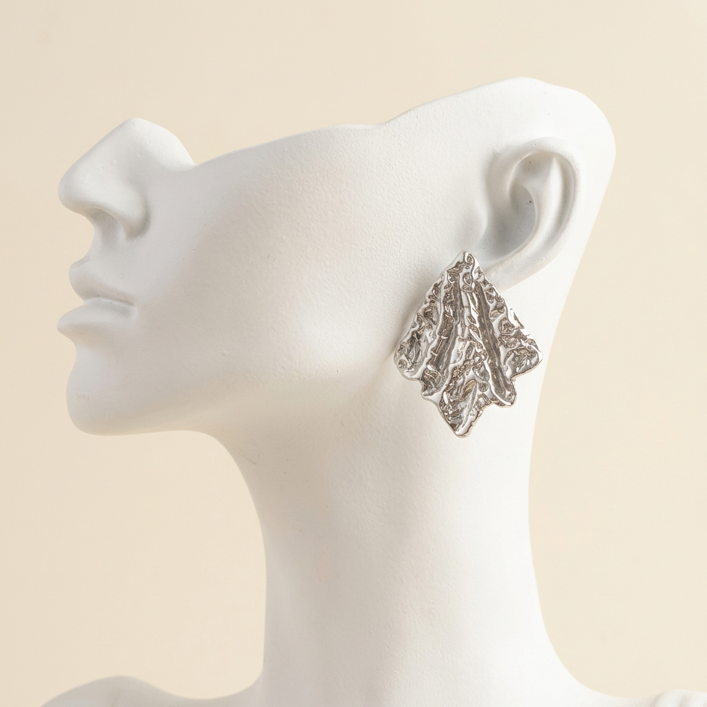 Silver-tone textured sculpted leaf earring on a white display bust